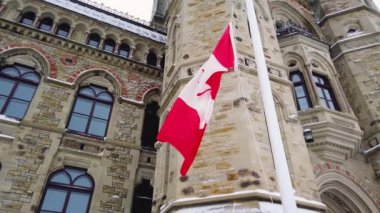 Kanada 'nın ulusal bayrağı, Ontario, Ottawa' daki Kanada Parlamento Tepesi 'ndeki üç binadan biri olan Doğu Bloğu binasının arka planında dalgalanmaktadır..