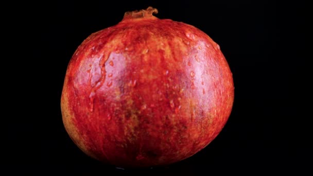 水滴は黒い背景に回転する赤いザクロの果実に落ちる — ストック動画