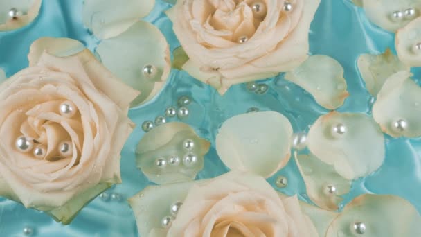 Perły Spadają Powierzchnię Wody Płatkami Kwiatami Beżowych Róż Niebieskim Tle — Wideo stockowe