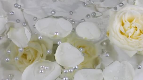 Perlen Und Weiße Rosenblätter Schwimmen Auf Der Wasseroberfläche Vor Dem — Stockvideo