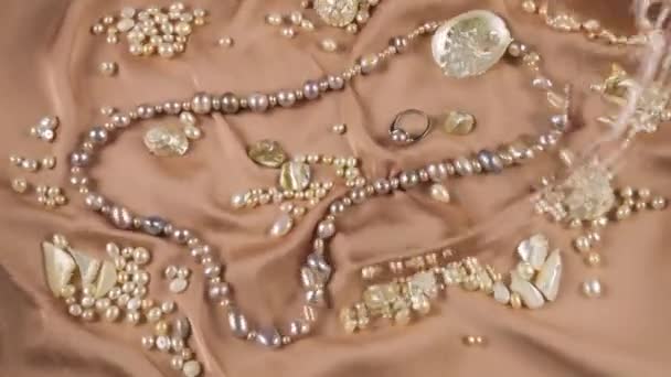ベージュの背景に真珠と母パールで作られた天然真珠とジュエリー 透明な水面のリップル — ストック動画