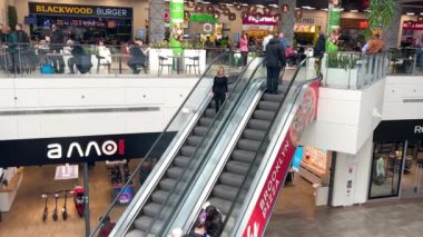 LVIV, UKRAINE - 25 Mart 2024: Modern bir alışveriş ve eğlence merkezinde yürüyen merdivenlerle açık bir alanın üst görüntüsü.