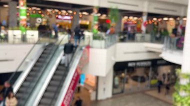 Modern bir alışveriş ve eğlence merkezinde yürüyen merdivenli açık bir alanın en üst görüntüsü. Odaklanamıyorum.