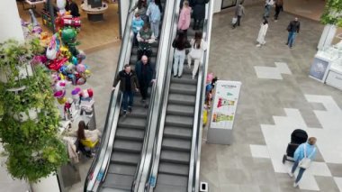 LVIV, UKRAINE - 25 Mart 2024: Modern bir alışveriş ve eğlence merkezinde yürüyen merdivenlerle açık bir alanın üst görüntüsü.