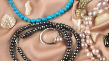 Suyun altında bej renkli ipek arka planda değerli taşlar ve incilerden yapılmış mücevherler. Temiz suyun yüzeyinde dalgalanmalar.