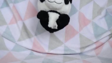 Doldurulmuş ve pofuduk oyuncak panda yumuşak bir bebek battaniyesine düşer. Yavaş çekim.