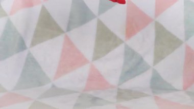 Doldurulmuş ve pofuduk peluş oyuncak leylek yumuşak bir bebek battaniyesine düşer. Yavaş çekim.