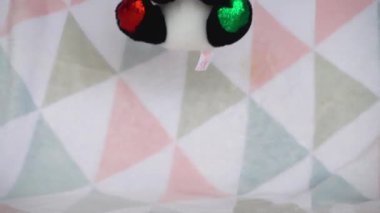 Doldurulmuş ve pofuduk oyuncak panda Noel Baba şapkası takmış yumuşak bir bebek battaniyesine düşmüş. Yavaş çekim.