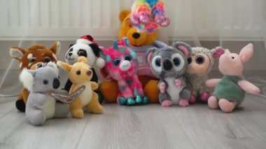 Doldurulmuş ve pofuduk peluş peluş ve gökkuşağı oyuncak koyunları oyun sahasındaki lamine zemine diğer oyuncakların arka planına düşerler. Yavaş çekim.