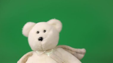 Doldurulmuş ve pofuduk oyuncak ayıcıklar. Melek kanatlarıyla yeşil arka planda dans edip oynuyorlar..