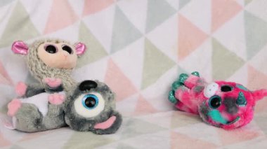 Doldurulmuş ve pofuduk peluş ve gökkuşağı oyuncakları koyun yumuşak bir bebek battaniyesine düşer. Yavaş çekim.