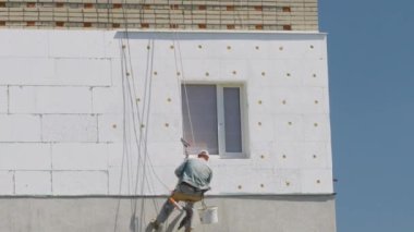 Yüksek irtifa tırmanışçıları köpük paneller kullanarak bir evin duvarını yalıtmak için çalışırlar..