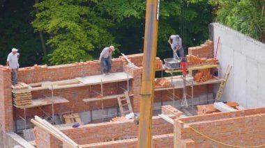 LVIV, UKRAINE - 2 Haziran 2024: inşaat alanı. İnşaat işçileri tuğlalardan bir evin duvarını inşa ediyorlar..