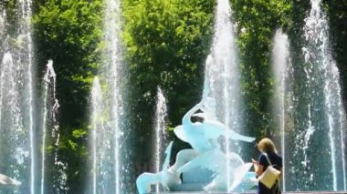 Bir fıskiyenin su fıskiyeleri ağaçların arka planına karşı. Yavaş çekim.