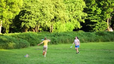 LVIV, UKRAINE - 10 Temmuz 2024: anne ve oğlu parktaki yeşil çimlerde ve çimlerde badminton oynuyorlar. Yavaş çekim.
