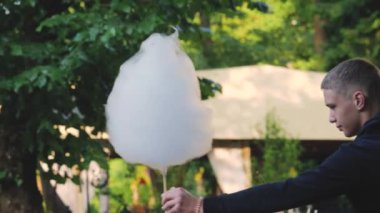 LVIV, UKRAINE - 10 Temmuz 2024: Genç bir adam parkta bir kıza pamuk şeker satıyor.