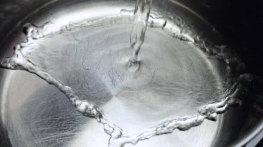 Su, metal bir tavanın dibine dökülür. Yavaş çekim.