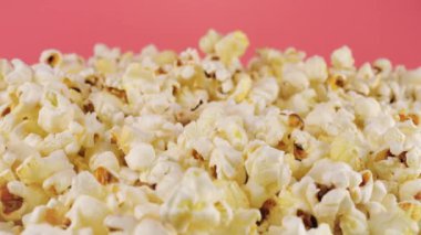 Pembe arka planda dönen patlamış mısır taneleri. Makro ve yakın plan.