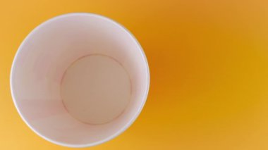 Patlamış mısır taneleri şeftali arka planda izole edilmiş kırmızı ve beyaz çizgili kovaya düşer. Atıştırmalık film, fast food kafe tatlı aperatif. Üst Manzara. Yavaş çekim.