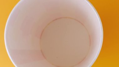 Patlamış mısır taneleri şeftali arka planda izole edilmiş kırmızı ve beyaz çizgili kovaya düşer. Atıştırmalık film, fast food kafe tatlı aperatif. Üst Manzara. Yavaş çekim.