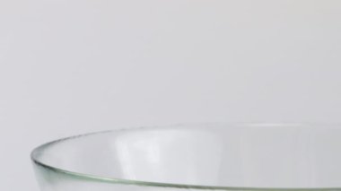 Beyaz arka planda izole edilmiş patlamış mısır taneleri cam şeffaf kaseye düşüyor. Ağır çekim. Atıştırmalık film, fast food kafe tatlı aperatif.