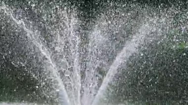 Çeşme fıskiyeleri ve düşen su damlaları güneş ışınlarında. Yavaş çekim.