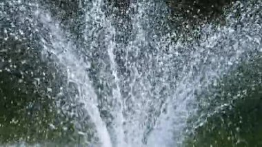 Çeşme fıskiyeleri ve düşen su damlaları güneş ışınlarında. Yavaş çekim.