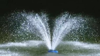 Parktaki gölete bakın. Ortasında güneş ışığıyla aydınlatılan bir çeşme var. Yavaş çekim.