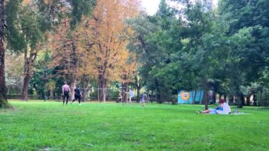 LVIV, UKRAINE - 15 Ağustos 2024: Bir erkek, bir kadın, bir kız ve bir çocuk yaz parkında badminton oynuyorlar.