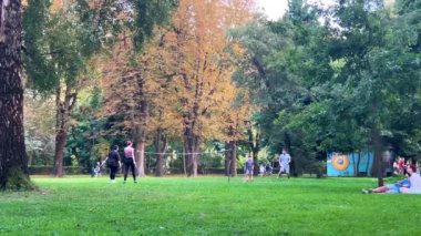 LVIV, UKRAINE - 15 Ağustos 2024: Bir erkek, bir kadın, bir kız ve bir çocuk yaz parkında badminton oynuyorlar.