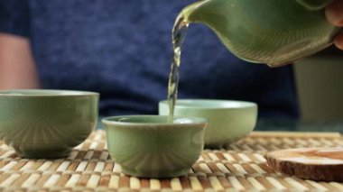 Gaiwan 'dan seramik chawanlara yeşil çay dökülüyor. Doğu Asya tarzı çay seremonisi.