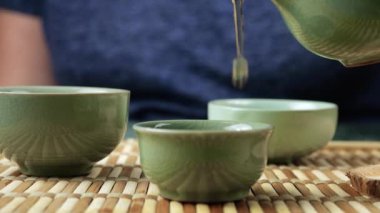 Gaiwan 'dan seramik chawanlara yeşil çay dökülüyor. Doğu Asya tarzı çay seremonisi.