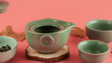 İyileştirilmiş çay yaprakları pembe arka planda seramik gaiwan 'ın içine dökülür. Doğu Asya tarzı çay töreni.
