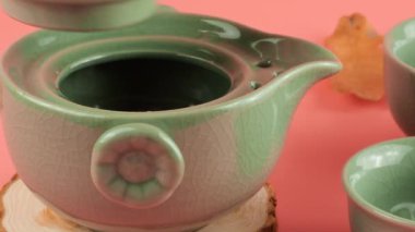 Pembe arka planda çay yaprakları olan bir gaiwan 'a sıcak su dökmek. Doğu Asya tarzı çay töreni.