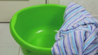 Açık renkli yazlık erkek gömlekleri plastik bir çamaşır leğenine atılır. Çamaşır yıkama, kıyafet düzenleme ve evi temizleme teması..