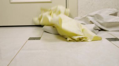 Erkek pantolonu ve gömlekleri fayanslı zemine atılır. Çamaşır yıkama, kıyafet düzenleme ve evi temizleme teması..