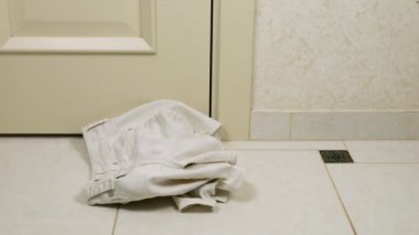 Beyaz ve mavi renkli yaz kadın kıyafetleri fayanslı zemine atılır. Çamaşır yıkama, kıyafet düzenleme ve evi temizleme teması..