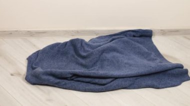 Örgü süveterler, eşarplar, gri-mavi tonlarda yün şapkalar odanın zeminine atılır. Çamaşır yıkama, kıyafet düzenleme ve evi temizleme teması..