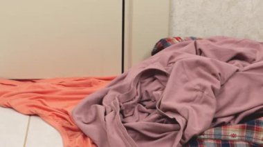 Parlak renkli kadın kıyafetleri fayanslı zemine atılır. Çamaşır yıkama, kıyafet düzenleme ve evi temizleme teması..