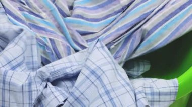 Renkli erkek gömlekleri plastik çamaşır leğenine atılır. Çamaşır yıkama, kıyafet düzenleme ve evi temizleme teması..