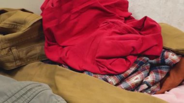 Renkli tişörtler ve tişörtler yerdeki çamaşır yığınına atılır. Çamaşır yıkama, kıyafet düzenleme ve evi temizleme teması..