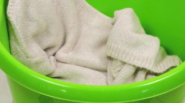 Örgü süveterler, atkılar, gri-mavi tonlarda yün şapkalar plastik bir çamaşır leğenine atılır. Çamaşır yıkama, kıyafet düzenleme ve evi temizleme teması..