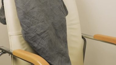 Erkek ve kadın kıyafetleri, pantolonlar, gömlekler, tişörtler ve uzun kollular sandalyenin üzerine atılır..