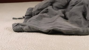 Erkek ve kadın kıyafetleri, pantolonlar, gömlekler ve tişörtler yatağa atılır..