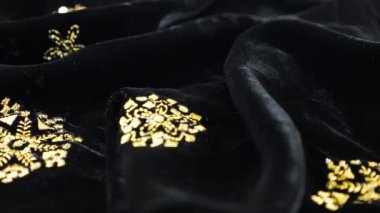 Altın işlemeli, gösterişli siyah ipek kumaş kadife kumaş. Tekstil arka planı. Tema tasarımı, moda, terzilik ve aksesuarlar. Güzel kıvrımlı kumaş.