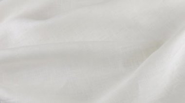 Beyaz keten kumaşın yumuşak kıvrımları vitrinde dönüyor. Tekstil arka planının üst görüntüsü. Tema tasarımı, moda, kıyafet terziliği.