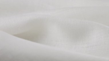 Beyaz keten kumaşın yumuşak kıvrımları vitrinde dönüyor. Tekstil arka planının yakın görüntüsü. Tema tasarımı, moda, kıyafet terziliği.