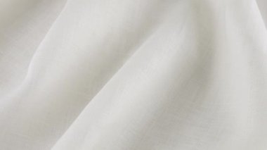 Beyaz keten kumaşın yumuşak kıvrımları vitrinde dönüyor. Tekstil arka planının üst görüntüsü. Tema tasarımı, moda, kıyafet terziliği.