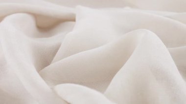 Dönen bir vitrindeki ince beyaz şifon kumaşın yumuşak kıvrımlarının yakın görüntüsü. Moda temalı dikiş aksesuarları ile tekstil arka planı.
