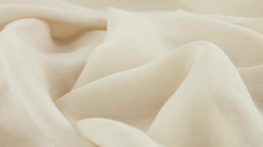Dönen bir vitrin üzerinde ince şeftali rengi beyaz şifon kumaşının yumuşak kıvrımlarının yakın çekim görüntüsü. Moda, tasarım, kumaş teması üzerine aksesuar dikebilen tekstil arka planı.